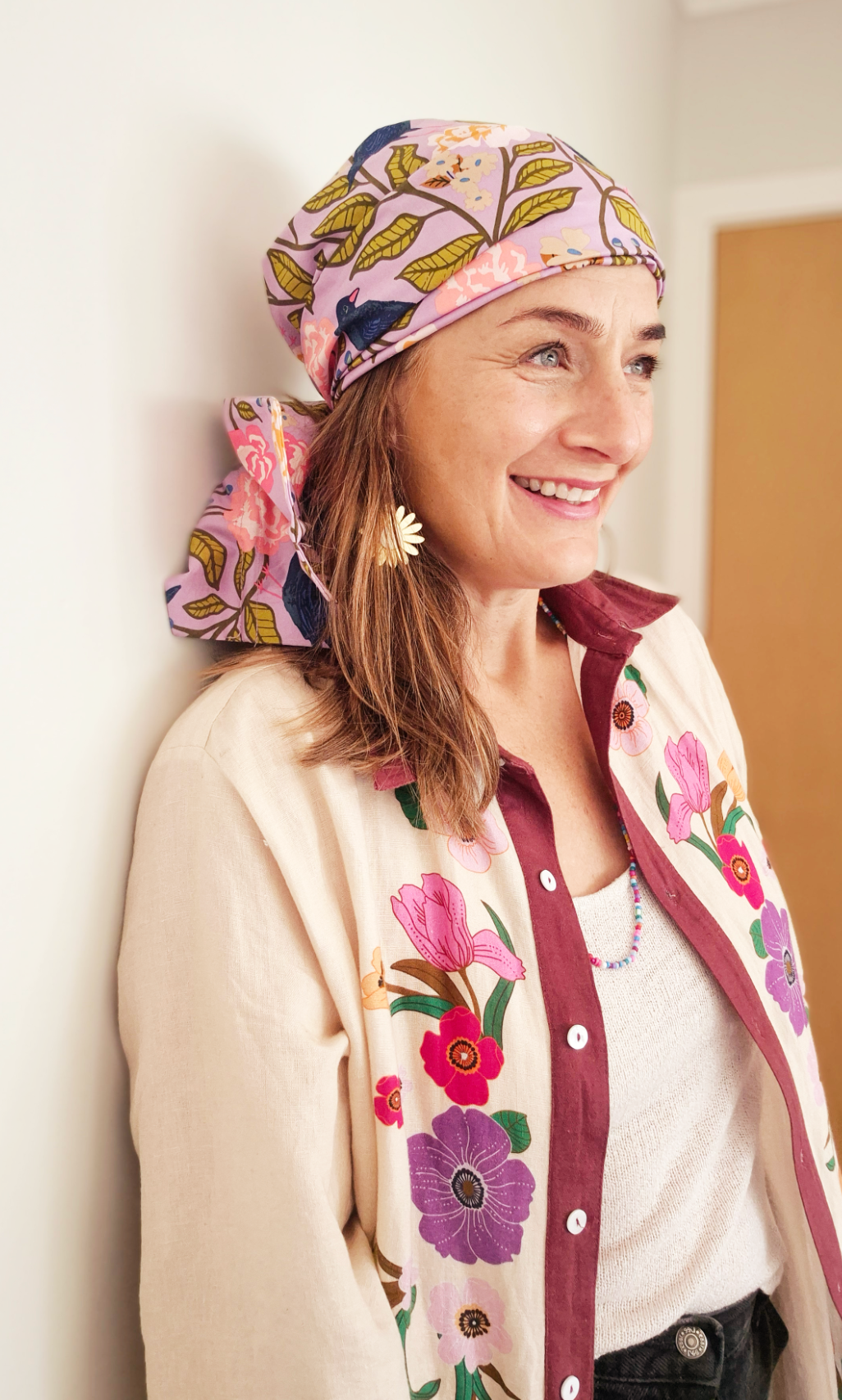 Head wrap for cancer hair loss – soft cotton turban by Celine Martine - Wired chemo head scarf for women – fashion headwear after treatment. Woman wearing a colourful headscarf and floral jacket indoors