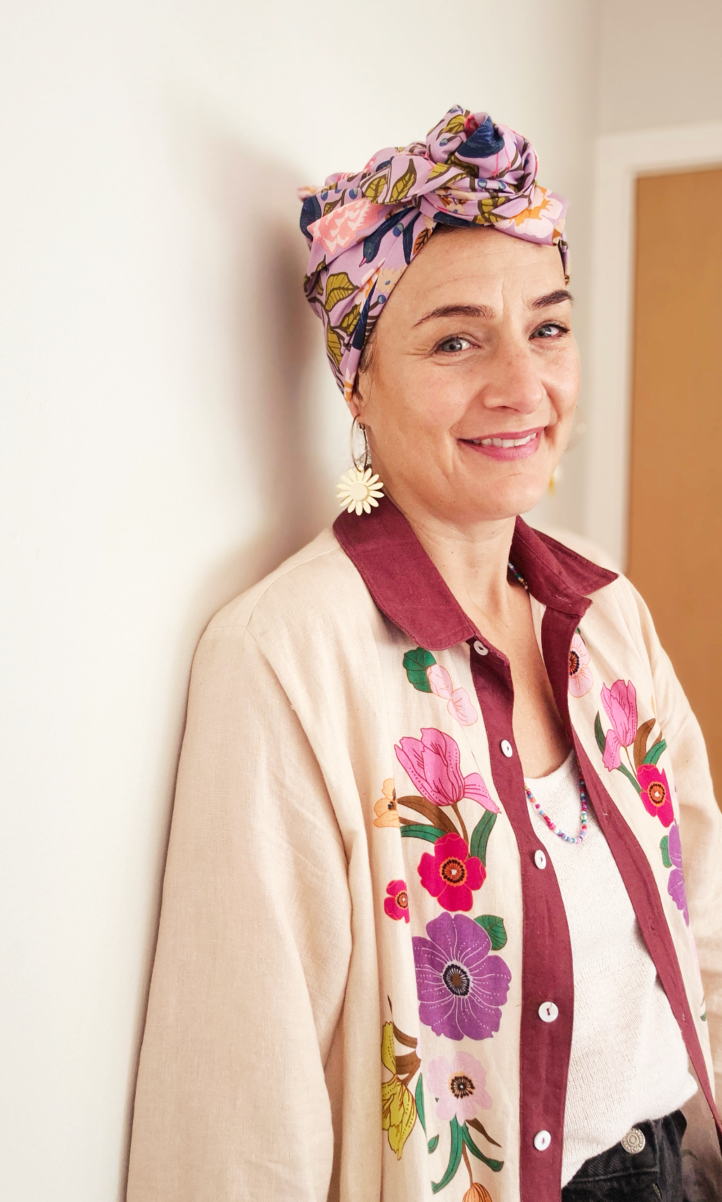 Head wrap for cancer hair loss – soft cotton turban by Celine Martine - Wired chemo head scarf for women – fashion headwear after treatment. Woman wearing a floral headscarf and embroidered jacket indoors.