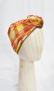 Side view of Celine Martine Josephine Head Wrap in Ember print, wrapped in a sculptural turban style with painterly stripes and concealed wire
