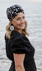 Portrait of Marion Lecesne in wired head Wrap and Earrings that say "Stop violence against women"